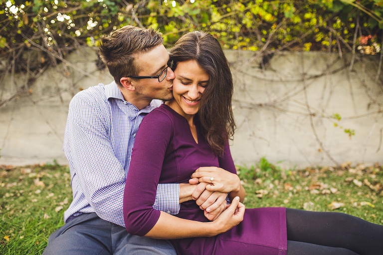 couple sitting down and guy kissing girl on cheek