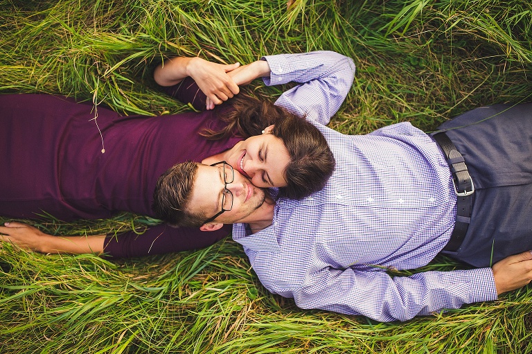 couple laying in grassing and smiling in freeland michigan