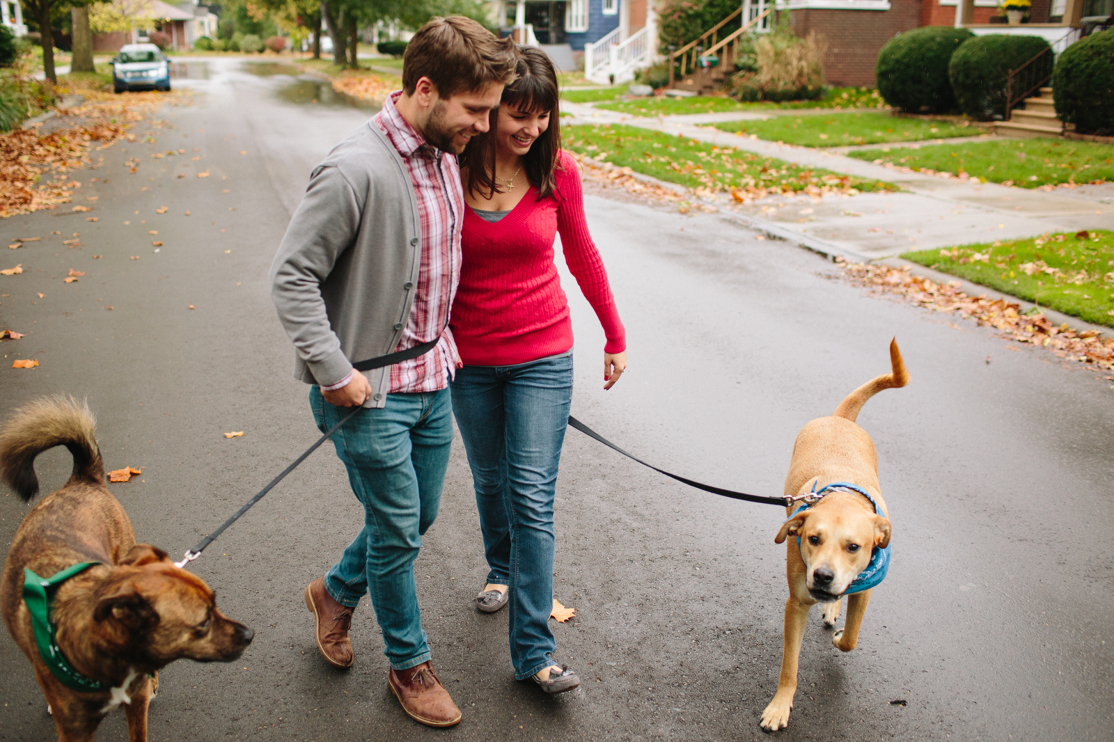 couple walks their dogs down neighborhood street