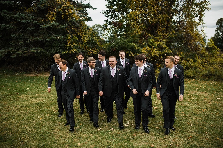 Groomsmen walking in field.